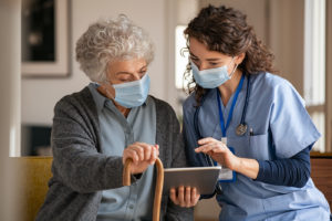 Doctor and senior woman going through medical record on digital tablet