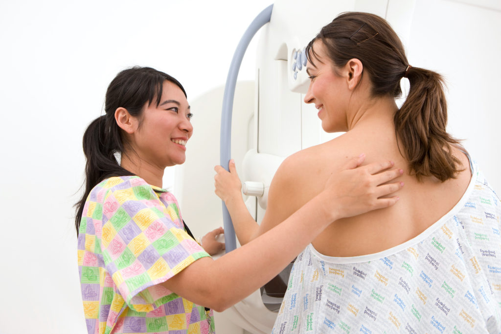 A candid shot of radiologist attending a patient on a mammogram machine