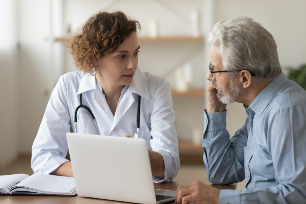 Young female doctor consulting with a older male patient