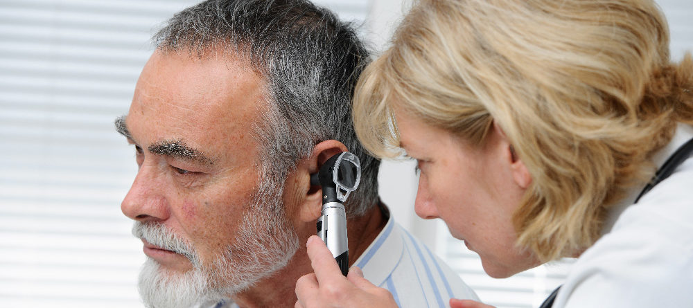 Doctor examines man's ear
