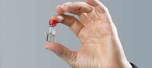 Hand holding a vial of Vasalgel male contraceptive