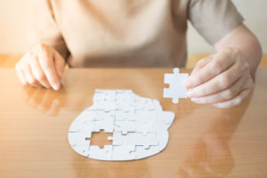 A seated person completing a puzzle of the human head