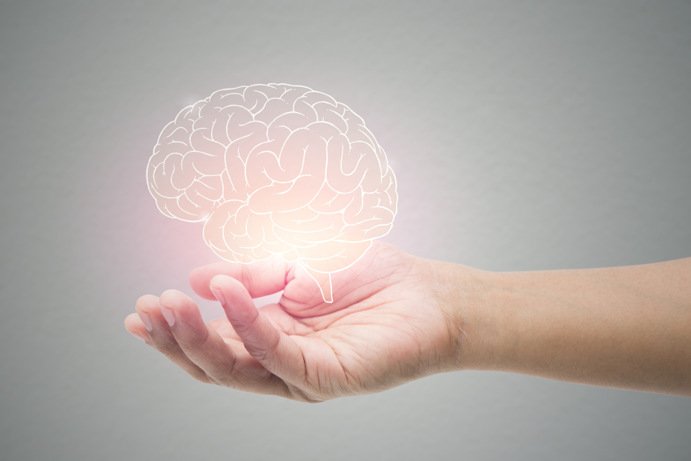 A hand holding a glowing brain to symbolize Alzheimer care