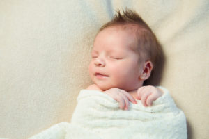Smiling newborn baby to show how the non-specific effects of common vaccines could save newborns