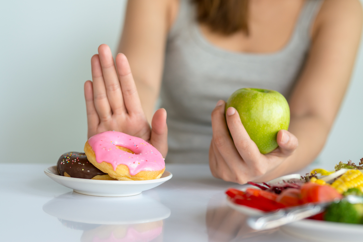 Young woman rejecting sugary food and choosing healthy food such as fresh fruit.