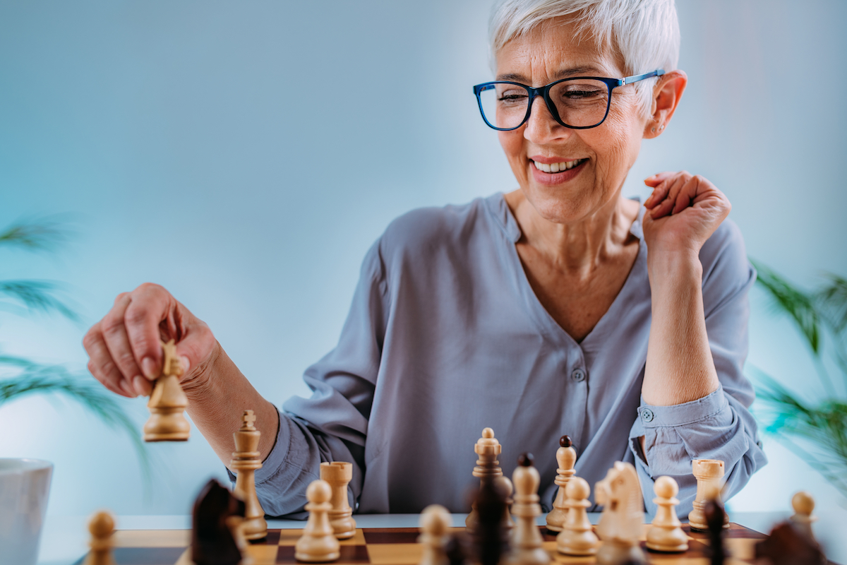 Senior woman playing chess as a cognitive rehabilitation activity.